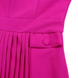 Détail de robe plissée magenta montrant la taille et une poche boutonnée élégante