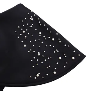 Close-up of elegant ruffled hem with pearl and silver bead embellishments on a black dress.