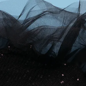 Close-up of black sequins and delicate mesh layers on an elegant evening dress