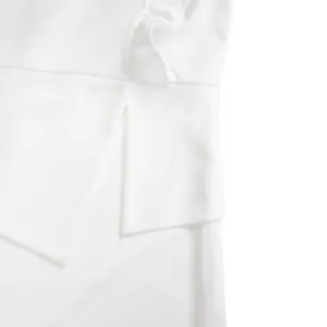 Gros plan de la robe crayon blanche avec des volants à la taille et des détails asymétriques.