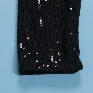 Close-up detail of black sequined dress sleeve showing shimmering texture and finish