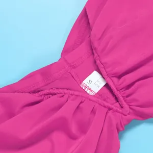 Close-up detail of hot pink ruched fabric with S size tag on fuchsia tube top dress.
