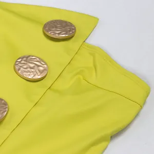 Detailansicht des limonengelben Overalls mit goldenen Strukturknöpfen und Stretchstoff