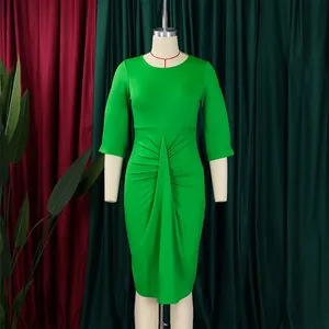 Detail van de geplooide taille van een groene nauwsluitende kokerjurk met driekwart mouwen