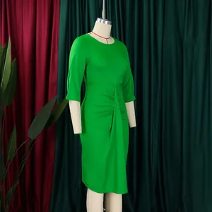 Gedetailleerd zijaanzicht van een elegante groene geplooide kokerjurk op een studiopop.