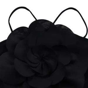 Close-up detail of an elegant black jumpsuit featuring a large 3D pleated flower decoration