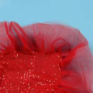 Macro detail showing vibrant red sequins and delicate mesh tulle fabric of dress