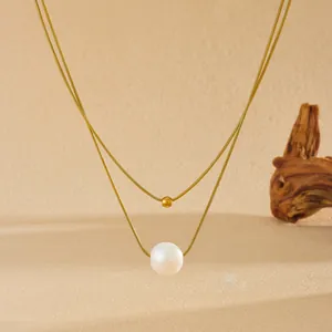 Gros plan détaillé d'un luxueux collier doré à deux rangs avec une perle naturelle