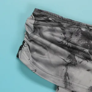 Κοντινό πλάνο στην γκρι tie-dye υφή υφάσματος και τη ραφή ενός εξώπλατου φορέματος με έναν ώμο.