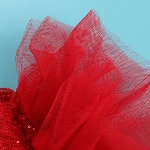 Macro view showing the intricate red mesh and sparkling sequin texture of the dress