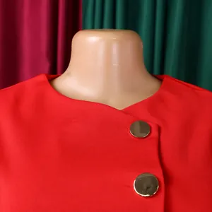 Close-up of elegant red women's top neckline with decorative gold buttons.