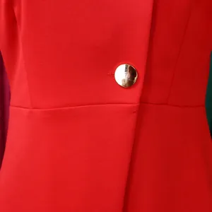 Close-up of red elegant women's blazer featuring a metallic gold button and textured fabric.