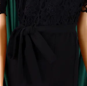 Close-up detail of elegant black lace jumpsuit with waist tie and hollowed patterns