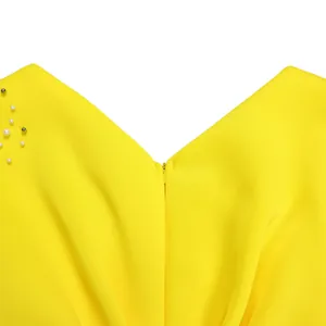 Detail view of yellow V-neck evening dress featuring elegant pearl beadwork accents