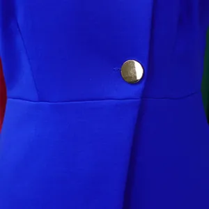 Close-up of royal blue fabric with elegant gold button detail on women's outfit