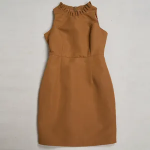 Detailansicht eines braunen ärmellosen Kleides mit elegantem Rüschenhals und Taille.