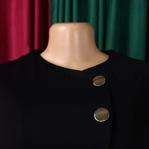 Close-up view of elegant black women's top featuring round neckline and gold buttons