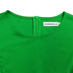 Detailweergave van groene kokerjurk met rits aan de achterkant en geweven neklabel