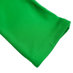 Detailopname van de groene stretchstof en het nette stiksel op de mouw van een kokerjurk