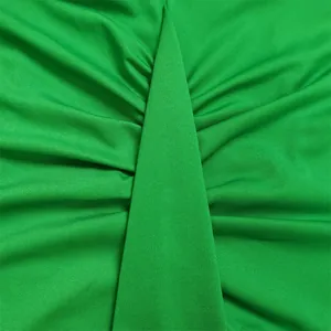 Detailopname van de levendige groene geplooide stof op een moderne kokerjurk