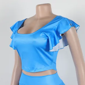 Detail van de ruchesmouwen en ronde hals van een levendig blauwe tweedelige set voor dames