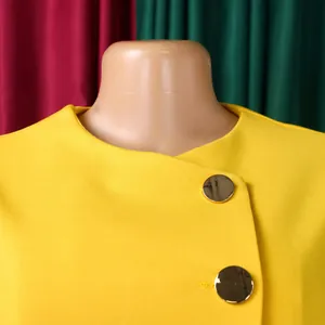 Detail of yellow elegant top featuring large round gold buttons and round neckline.
