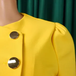 Detail of elegant yellow blazer with gold buttons and puff sleeves from two-piece set