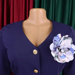 Dettaglio di abito blu navy con scollo a V, corsage floreale colorato e bottoni dorati