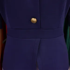 Dettaglio ravvicinato della vita di un abito blu navy con bottone dorato decorativo