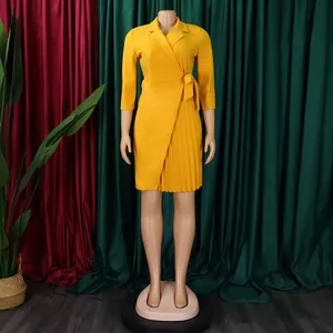 Détail de la robe portefeuille jaune à col tailleur avec ceinture et jupe plissée