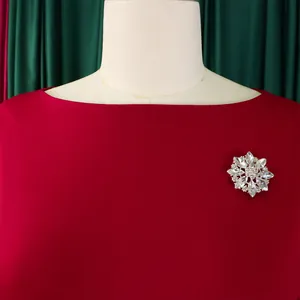 Dettaglio di un elegante abito rosso girocollo con spilla di cristallo a fiocco di neve