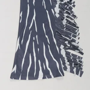Detail view of zebra print jumpsuit showing side fringe and flared leg opening