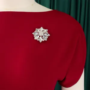 Elegante spilla a fiocco di neve in strass argentati su un abito rosso bordeaux