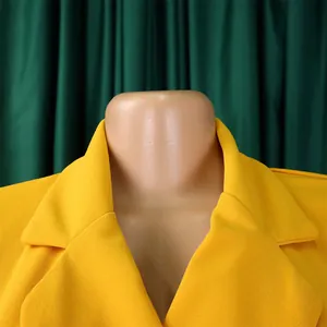 Détail du col d'un tailleur jaune sur une robe africaine plissée élégante et chic
