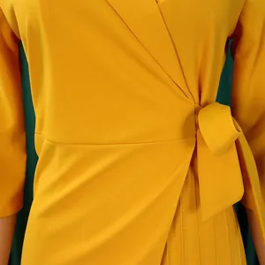 Gros plan d'une robe jaune avec un nœud latéral élégant et un tissu plissé sophistiqué.