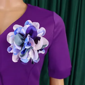 Dettaglio ravvicinato di un fiore in tessuto blu e lilla su un abito viola moda