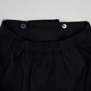 Detailaufnahme des Hosenbundes einer schwarzen Hose mit Gummizug und Knopfverschluss