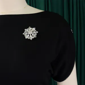 Elegante abito nero a maniche corte con girocollo e spilla a fiore in cristallo.