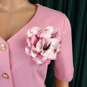 Dettaglio di un abito rosa finto due pezzi con elegante spilla floreale in tessuto