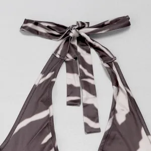 Detail of halter neck tie on elegant zebra print backless jumpsuit, soft fabric.