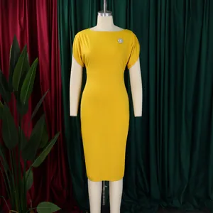 Elegante abito giallo a tubino a maniche corte con spilla argentata su un manichino bianco da sarto