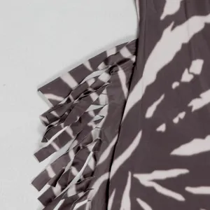 Close-up detail of stylish zebra print fabric with fringe trim on slim-fit jumpsuit.