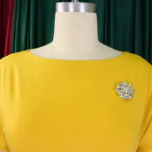 Primo piano di un vestito giallo a girocollo con spilla brillante a fiore di cristallo