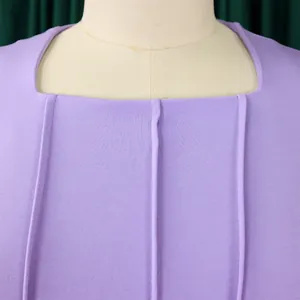 Close-up detail of the elegant square neckline and vertical pleats on a purple dress