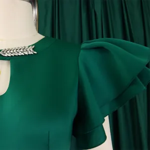 Detail view of emerald green dress with rhinestone collar and layered ruffle sleeves