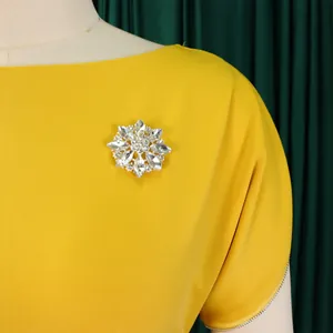 Elegante abito giallo a girocollo con dettaglio di spilla in strass scintillanti.