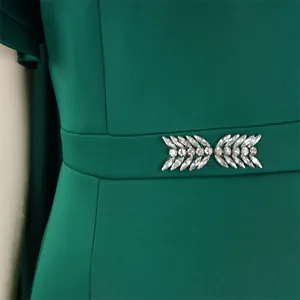 Exquisite close-up detail of emerald green evening dress featuring rhinestone leaf waist decor