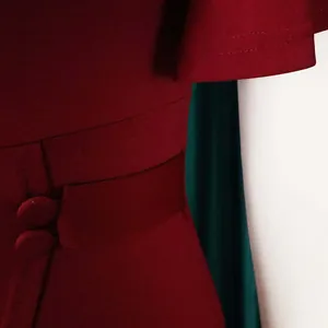 Close-up view of a wine red dress waistline with decorative buttons and ruffle sleeves