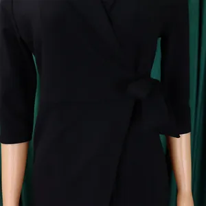 Détail d'une robe blazer noire grande taille avec ceinture élégante et jupe plissée.