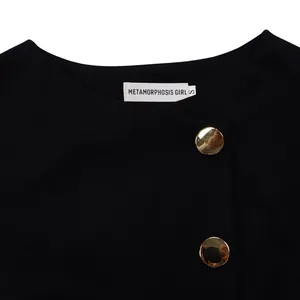 Detailed close-up of a black elegant top neckline with gold buttons and brand label